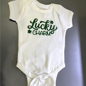 White cotton baby onesie with green flock lucky charm logo